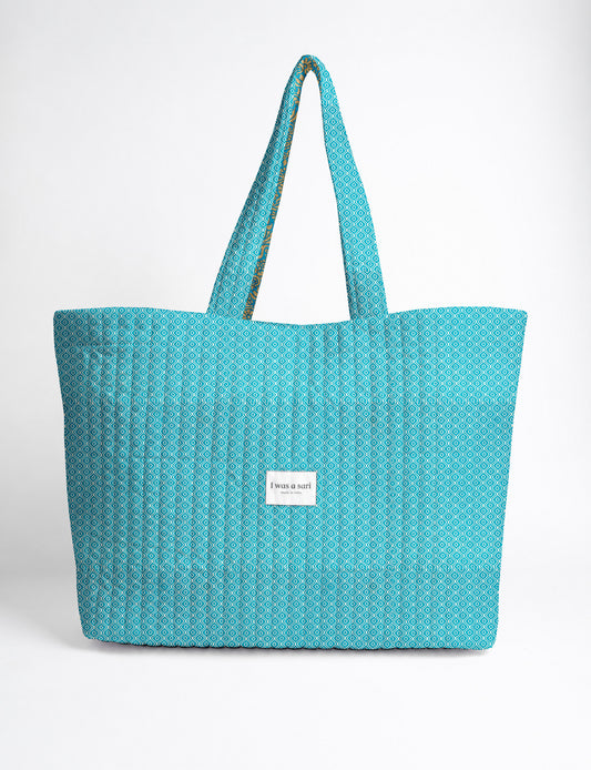 Quilted yellow tropical patterned beach bag with long handles and white label reading "I was a sari" front view