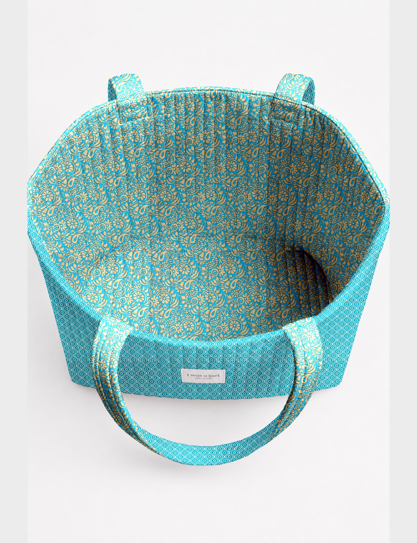 Quilted beach bag with yellow tropical exterior and red patterned interior, shown from top view with handles visible