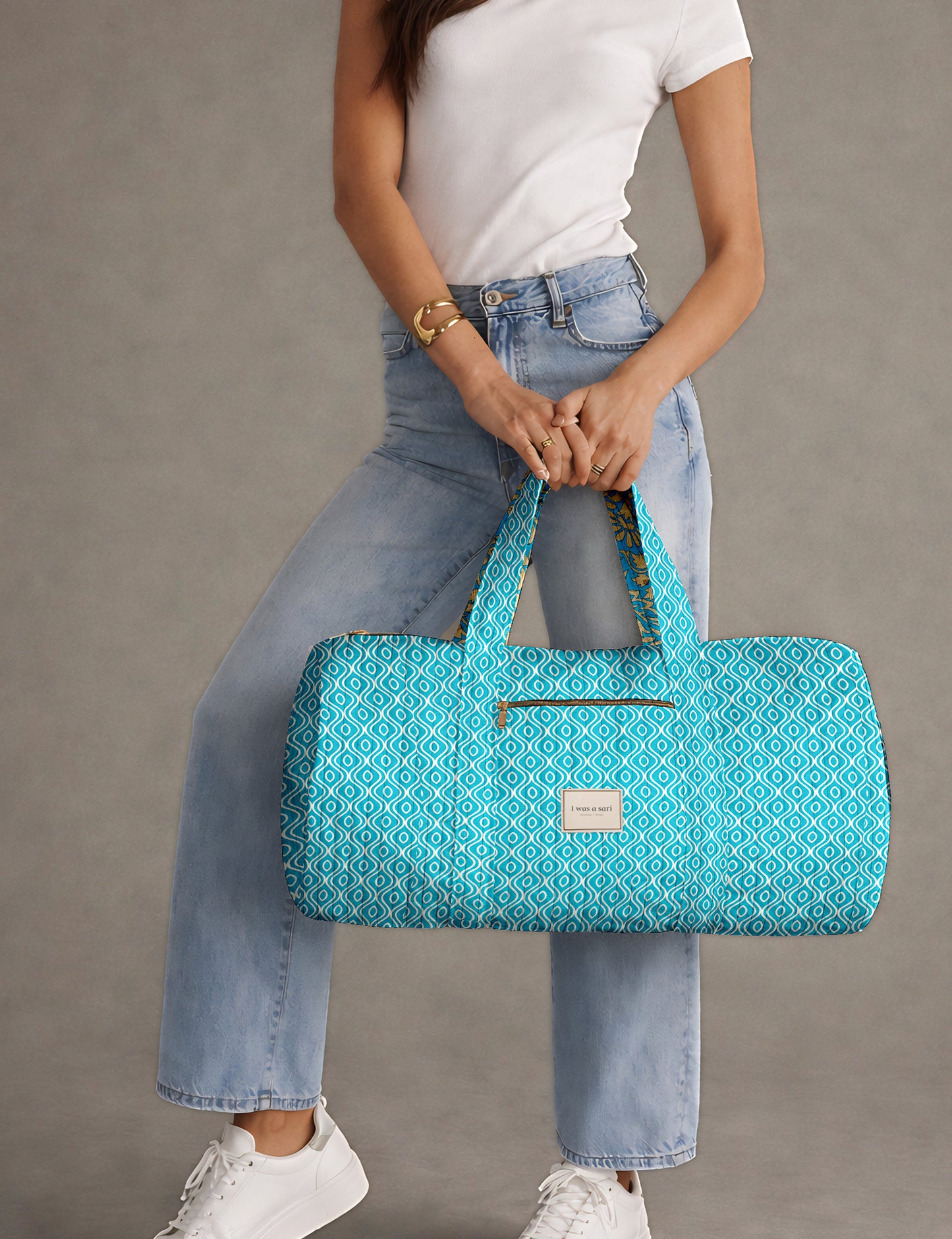 Brown paisley quilted bowling bag with front zipper pocket, held by person wearing white shirt and light blue jeans