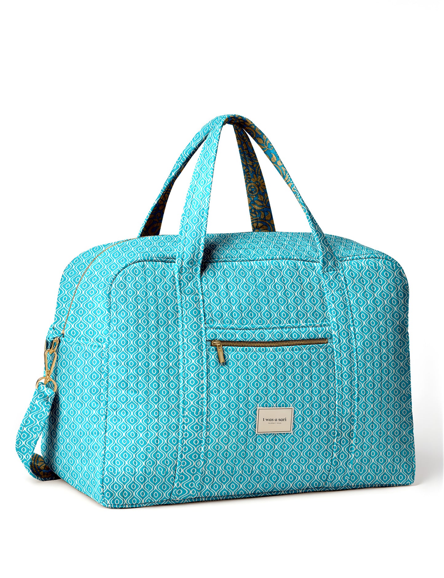 Brown quilted duffle bag with paisley pattern, front zip pocket, dual handles, and label reading "I was a sari"