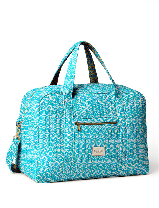 Brown quilted duffle bag with paisley pattern, front zip pocket, dual handles, and label reading "I was a sari"