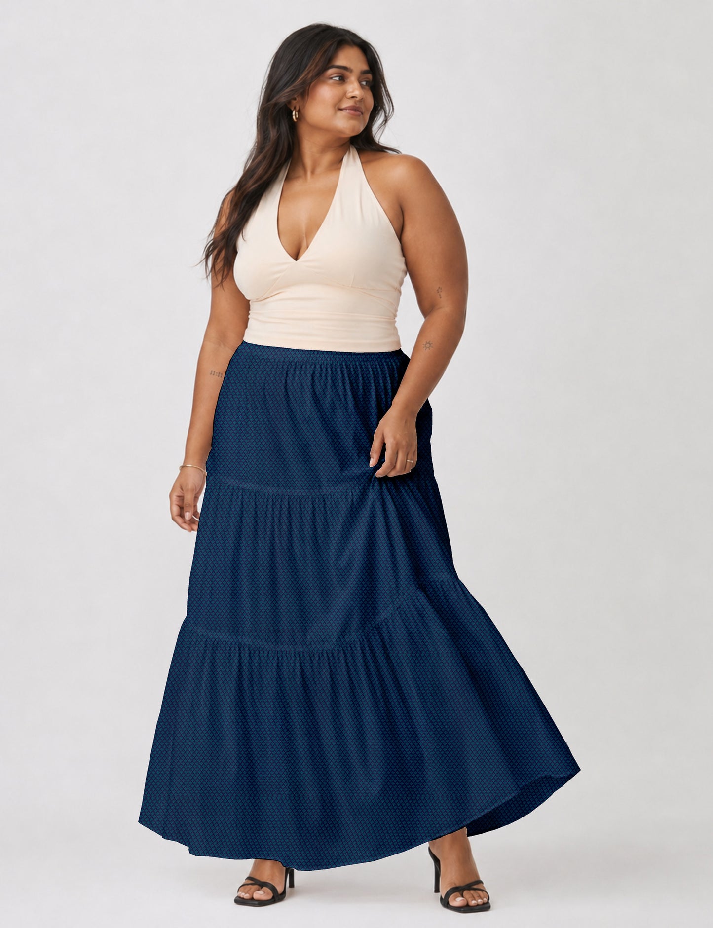 Woman wearing a yellow midi tiered skirt with a small geometric pattern, paired with a beige strapless top and white heels