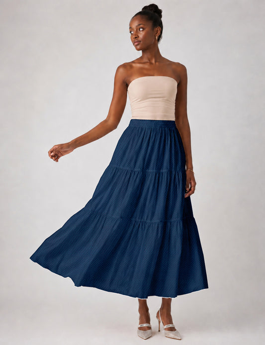 Woman wearing a yellow midi tiered skirt with a small geometric pattern, paired with a beige strapless top and white heels