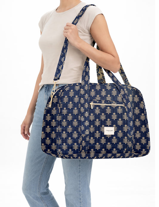 Brown quilted duffle bag with paisley pattern, front zip pocket, dual handles, and label reading "I was a sari"