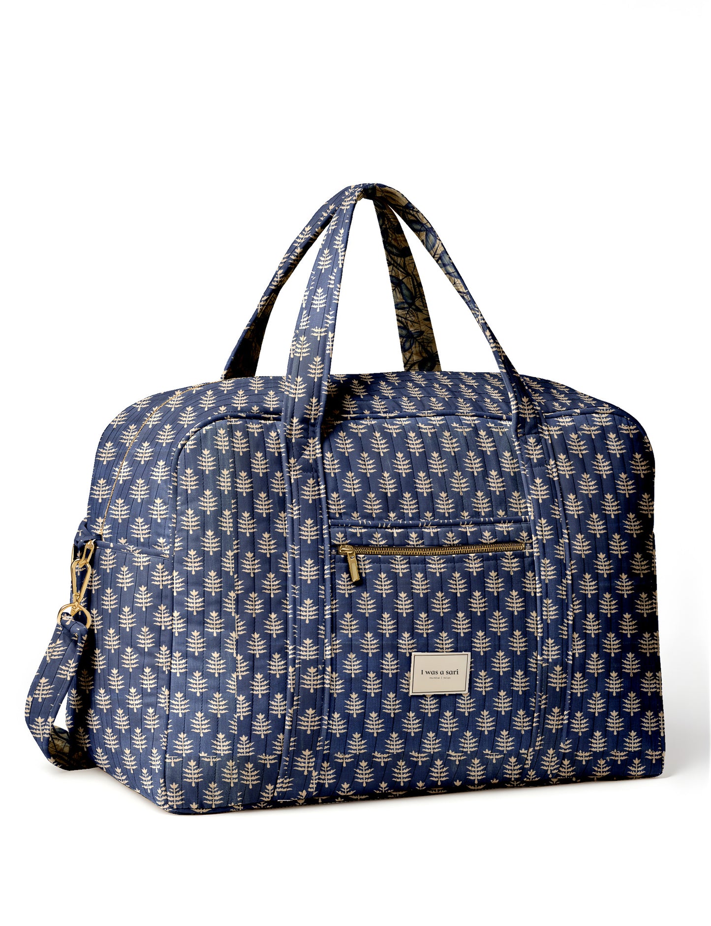 Brown quilted duffle bag with paisley pattern, front zip pocket, dual handles, and label reading "I was a sari"