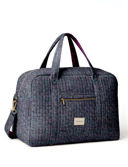Quilted duffle bag with blue and purple leaf pattern, front zipper pocket, dual handles, and detachable shoulder strap