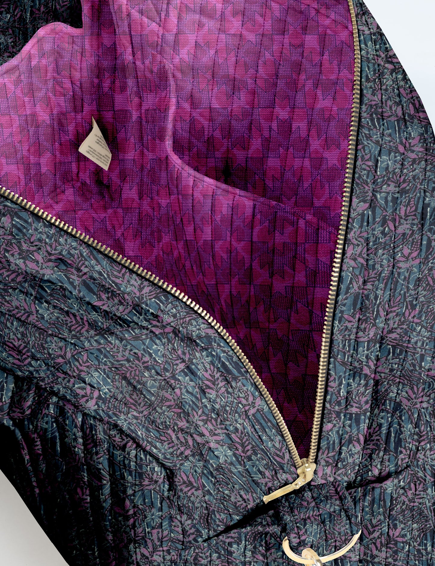 Quilted duffle bag with blue and purple leaf pattern exterior, gold zipper, and purple patterned interior lining