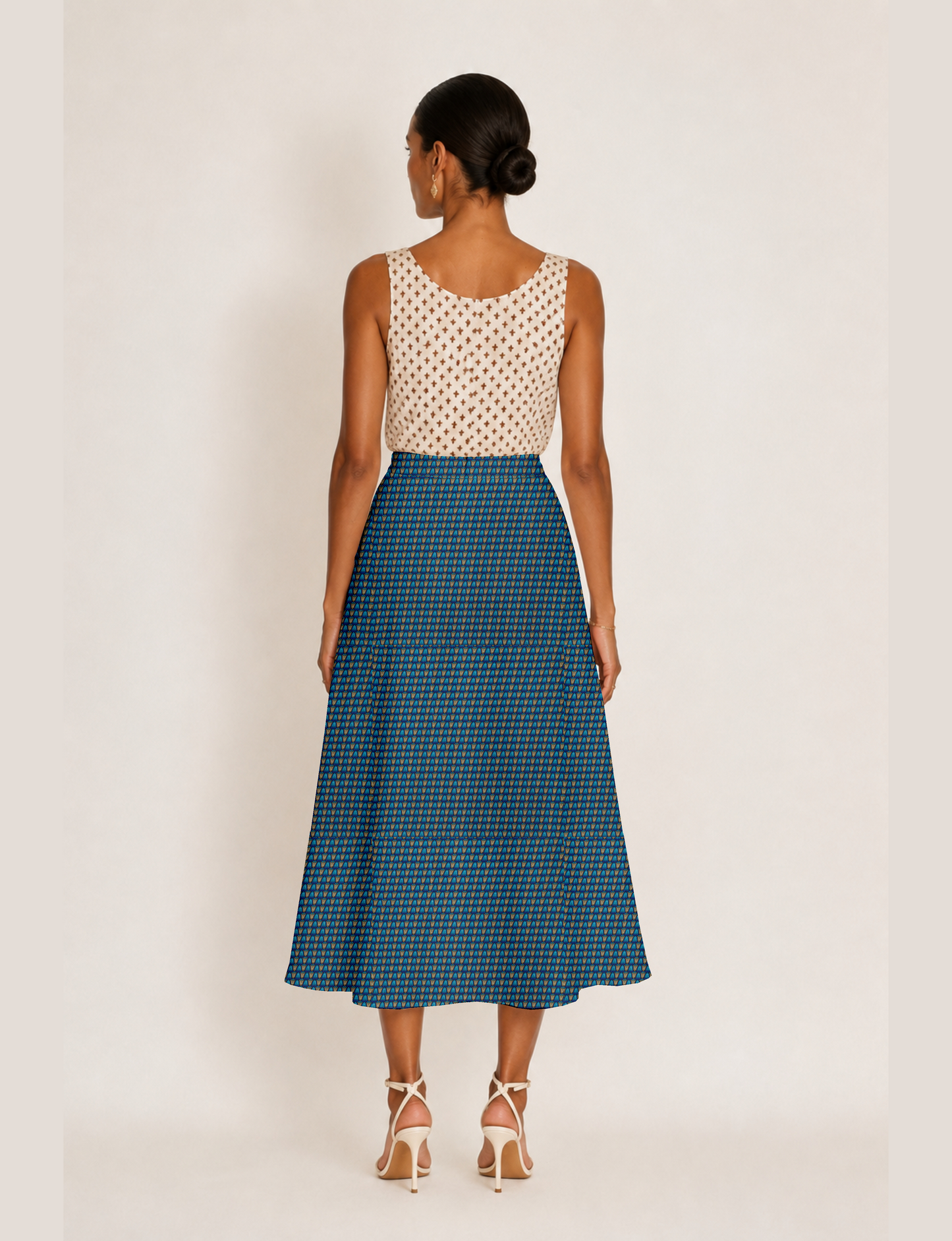 Woman wearing a yellow and black micro patterned A-line skirt with front slit, paired with beige sleeveless top and black