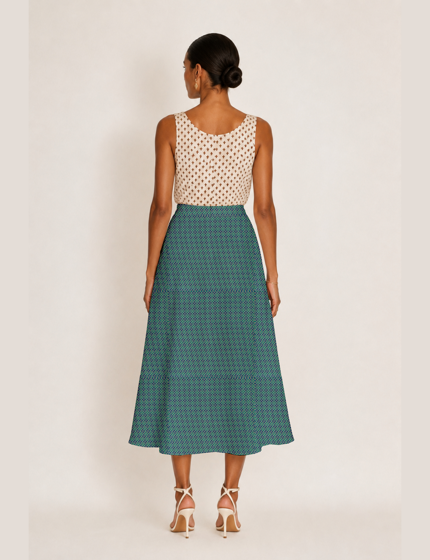 Woman wearing a yellow and black micro patterned A-line skirt with front slit, paired with beige sleeveless top and black
