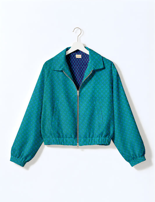 Blue bomber jacket with green micro pattern, front zipper, elastic cuffs and waistband, hanging on white hanger