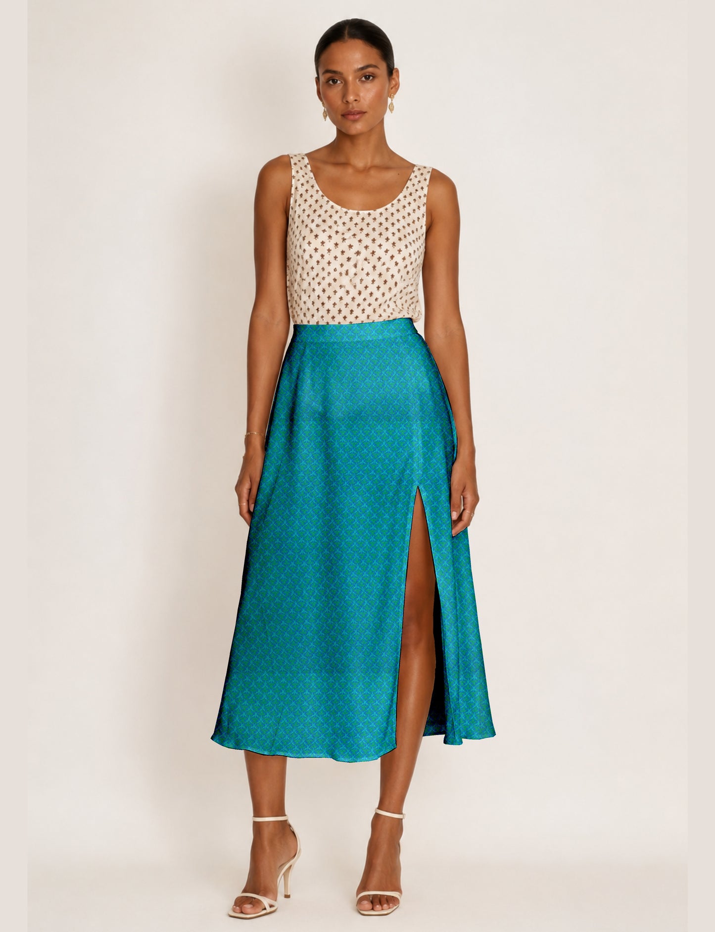 Woman wearing a blue A-line skirt with micro pattern and front slit, paired with a sleeveless beige top with brown print