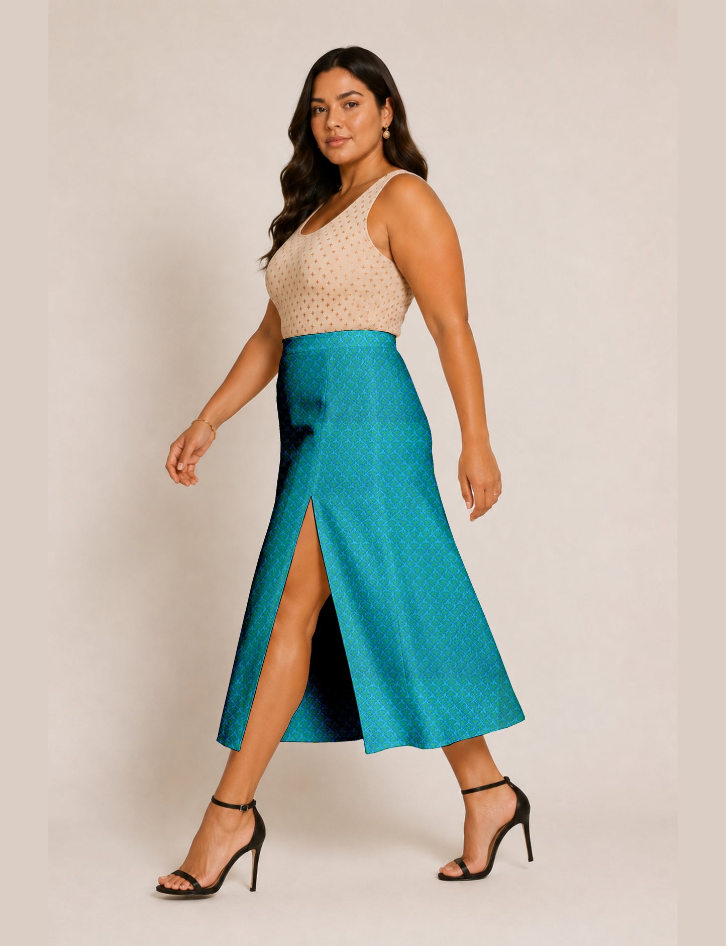 Woman wearing a blue A-line skirt with micro pattern and front slit, paired with a beige sleeveless top and black heels
