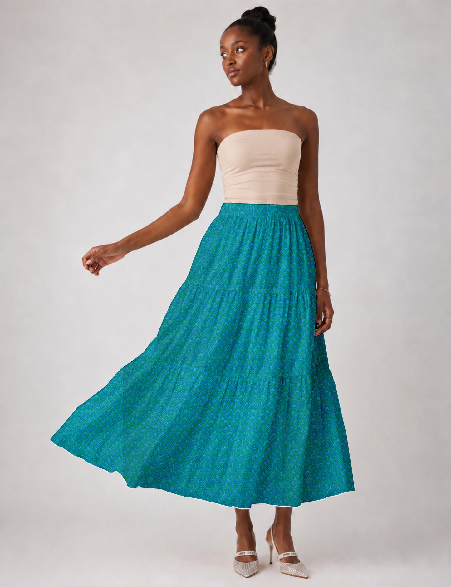 Woman wearing a blue midi tiered skirt with a micro pattern, paired with a beige strapless top and white heels