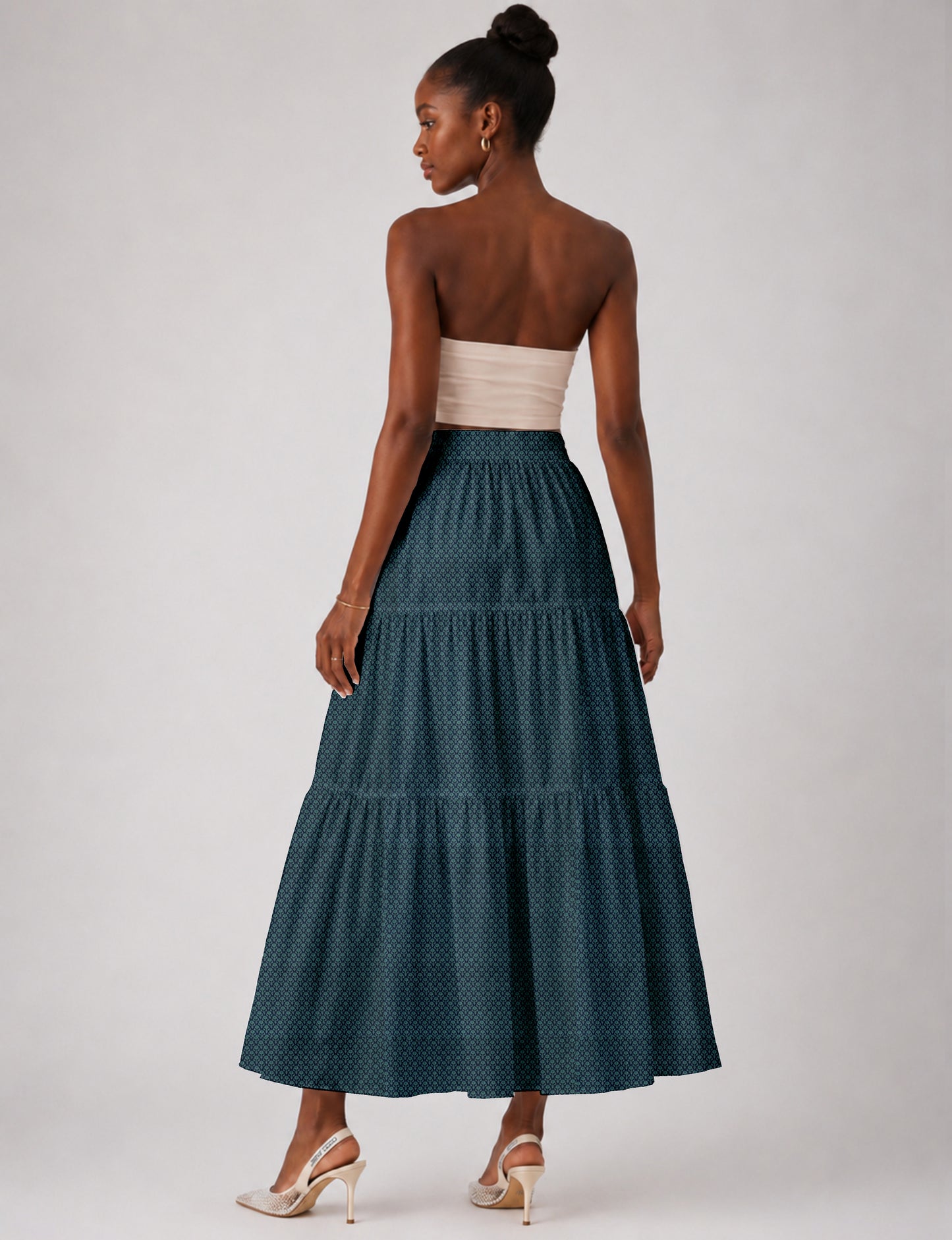 Woman wearing a yellow midi tiered skirt with a small geometric pattern, shown from the back, paired with beige top and