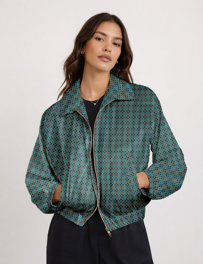 Woman wearing a blue bomber jacket with a micro geometric pattern, front zipper, and side pockets, shown from the waist up