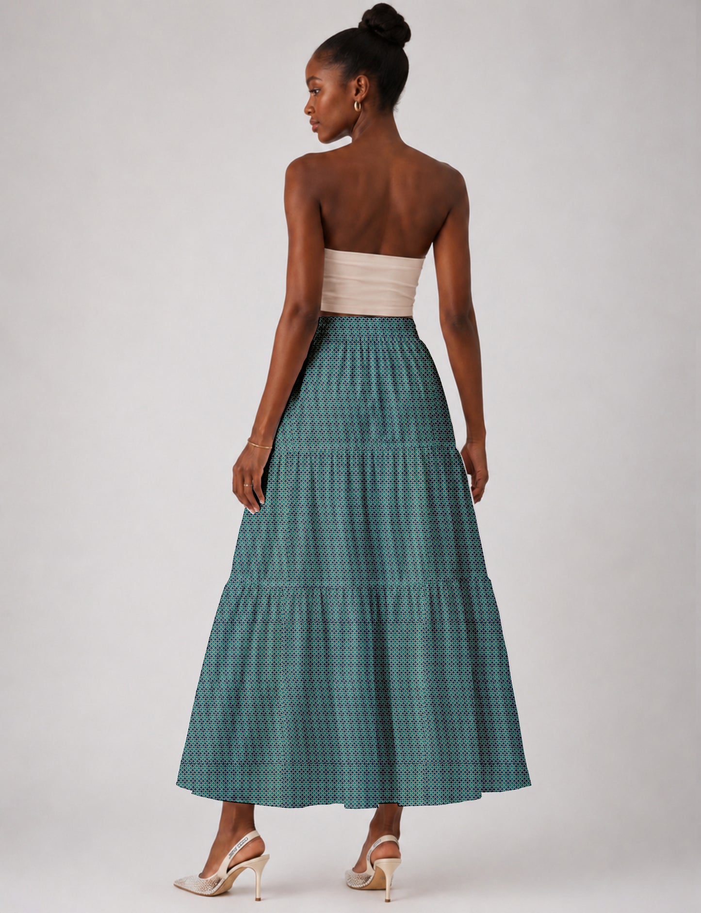 Woman wearing a yellow midi tiered skirt with a small geometric pattern, paired with a beige strapless top and white heels