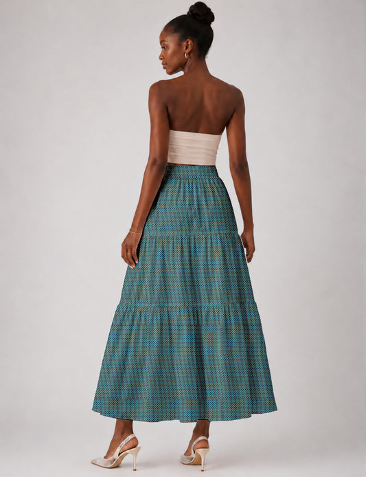 Woman wearing a yellow midi tiered skirt with a small geometric pattern, paired with a beige strapless top and white heels