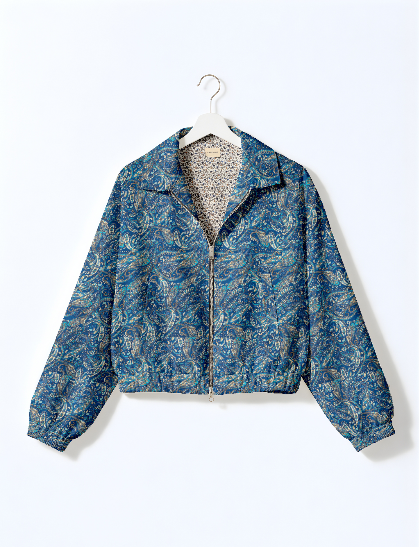 Women's cropped bomber jacket with twin metallic front zippers, welt pockets, elasticated hem and cuffs, and contrast sari print lining.