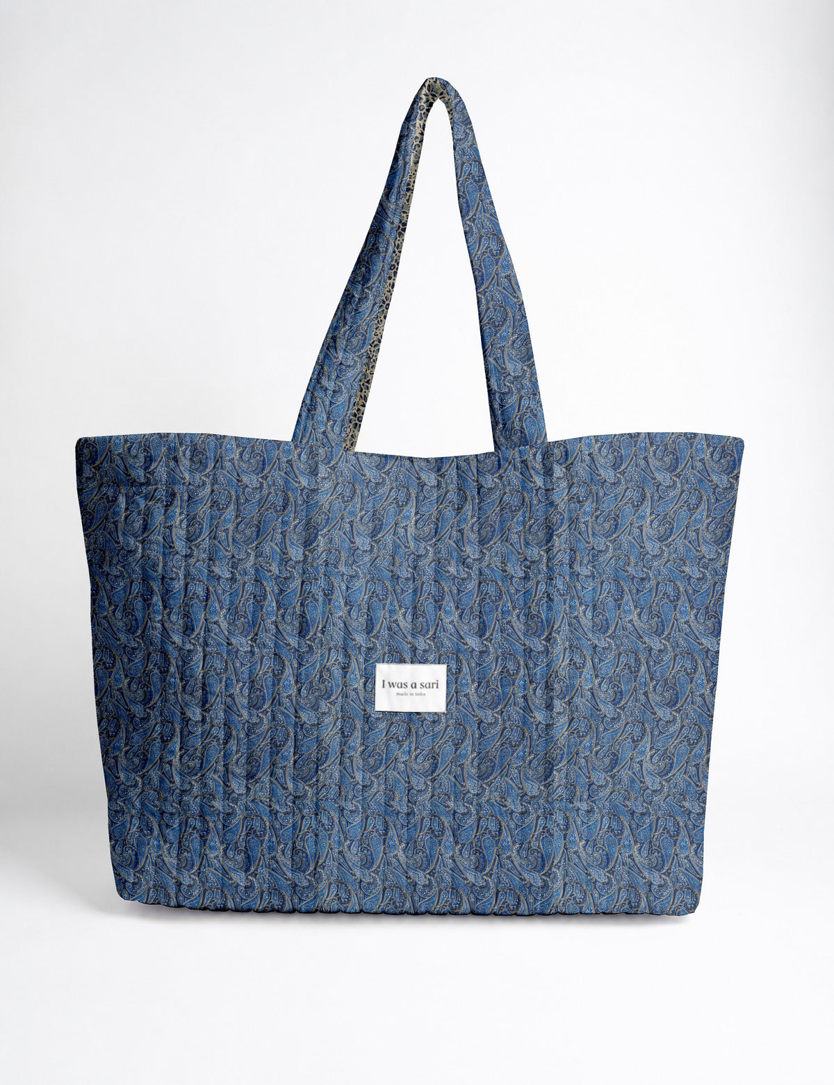 Quilted yellow tropical patterned beach bag with long handles and white label reading "I was a sari" front view