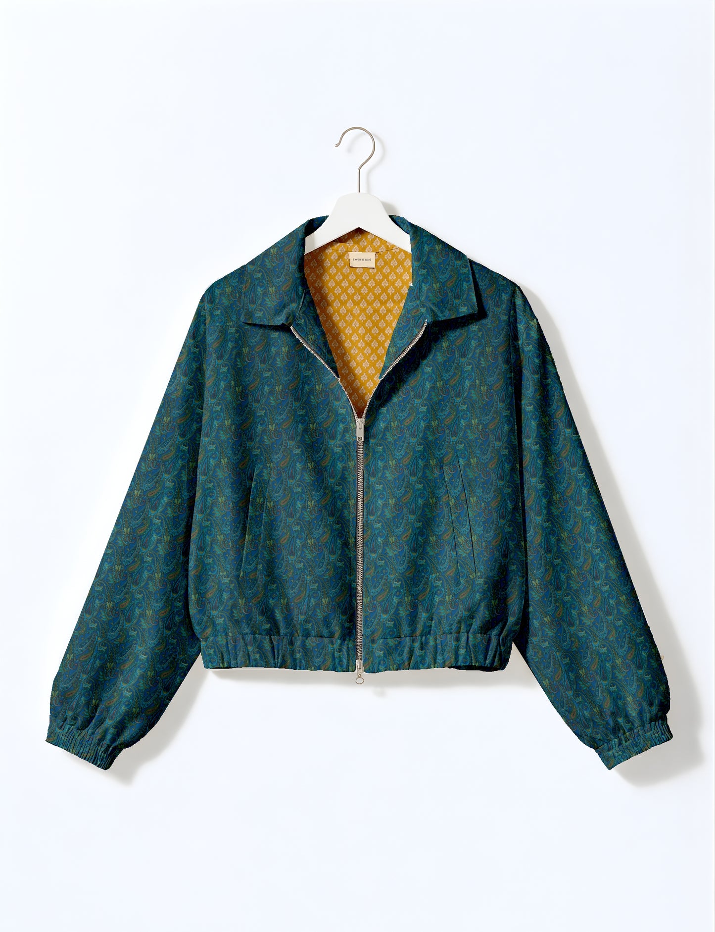 Yellow bomber jacket with micro geometric pattern, silver front zipper, elastic cuffs, and blue floral inner lining, hanging