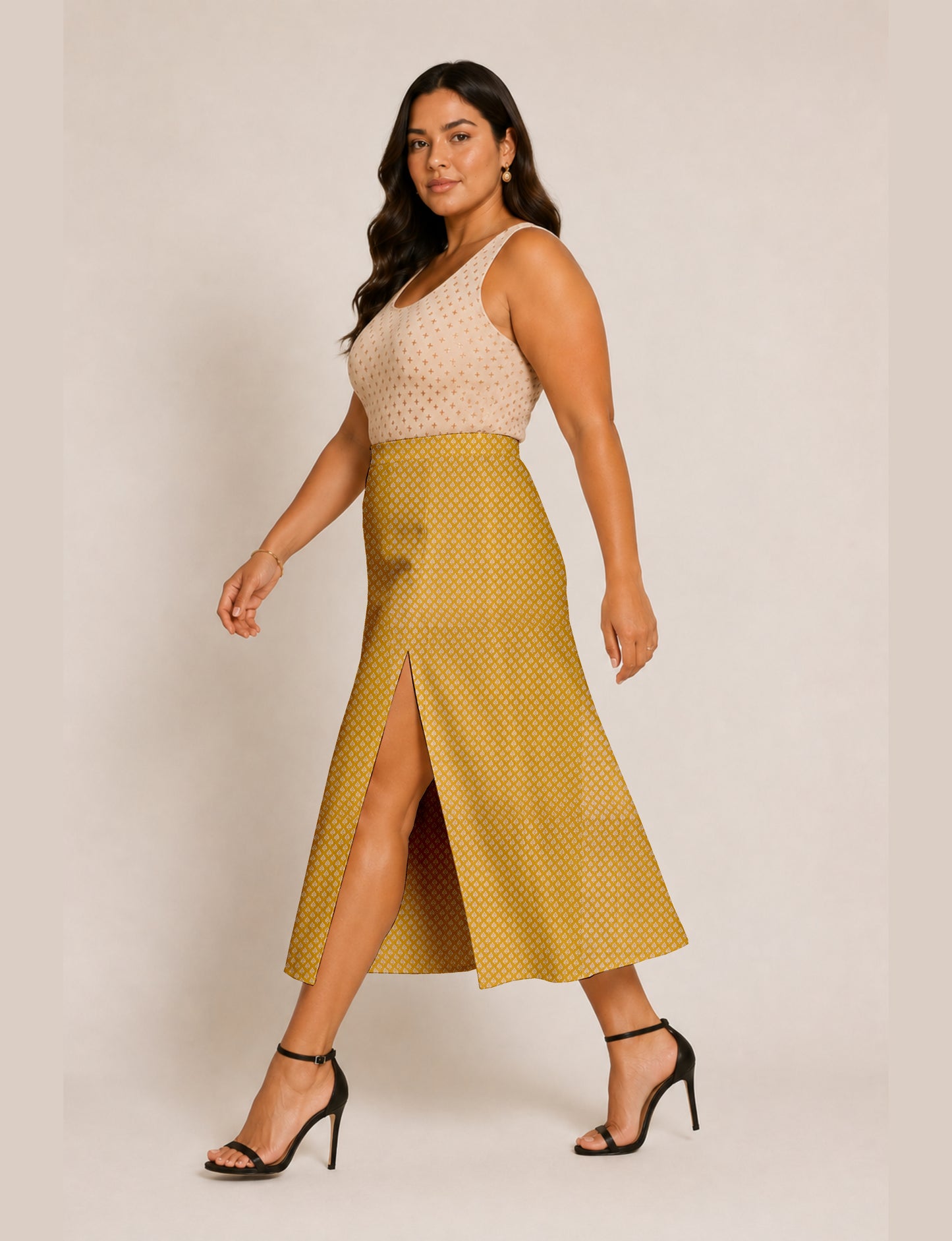 Woman wearing a yellow and black micro patterned A-line skirt with front slit, paired with beige sleeveless top and black