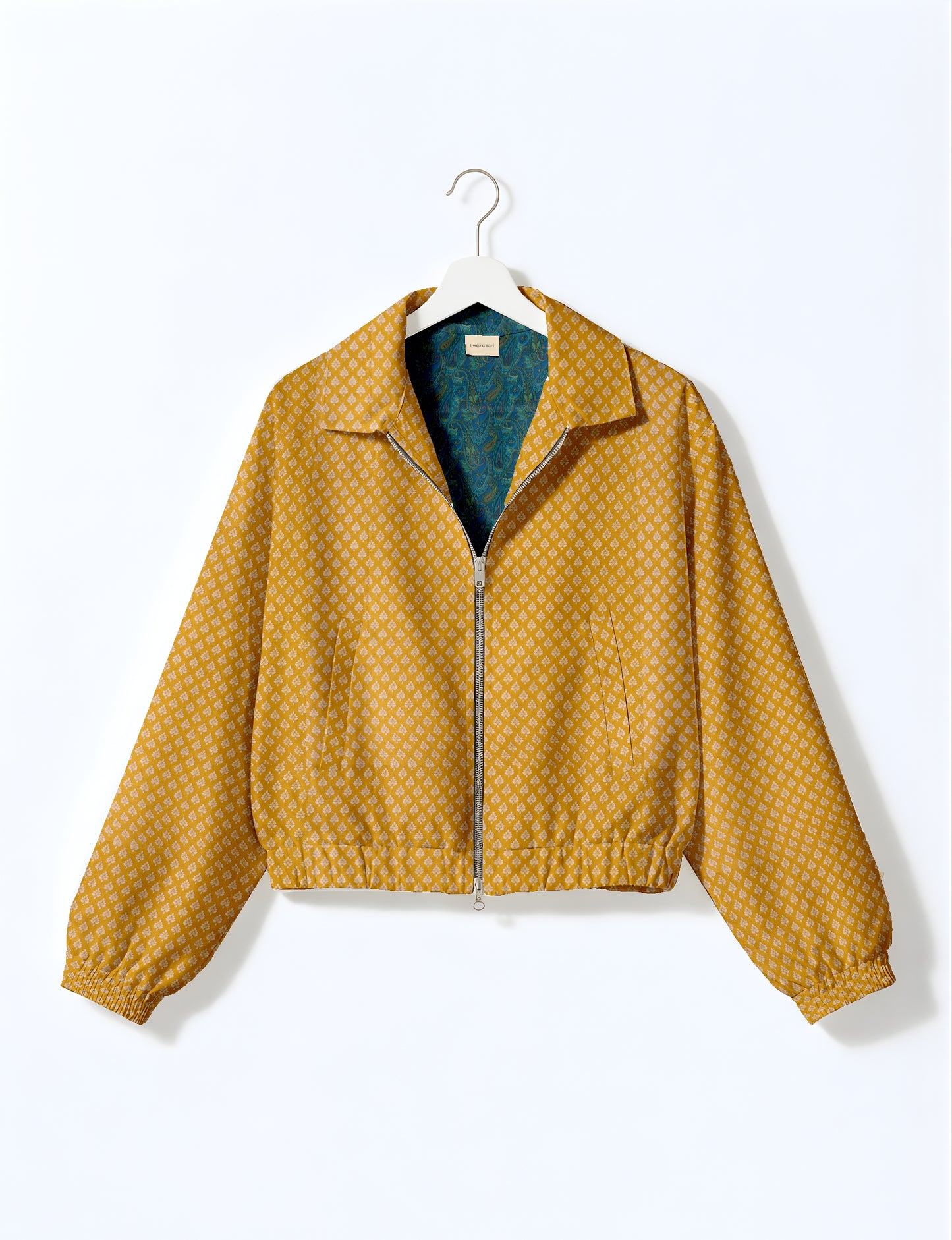 Yellow bomber jacket with micro geometric pattern, silver front zipper, elastic cuffs, and blue floral inner lining, hanging
