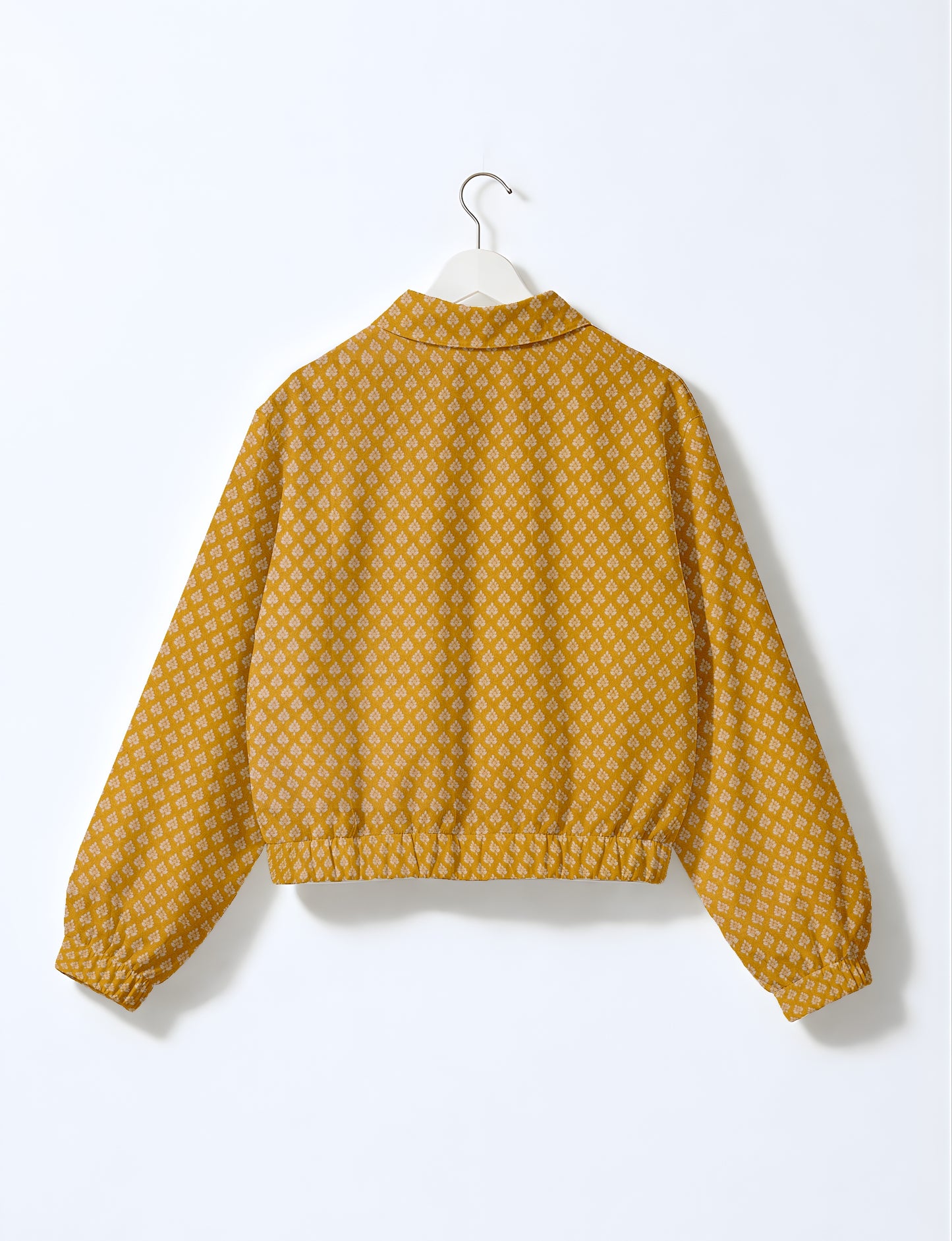 Yellow bomber jacket with micro diamond and floral pattern, elastic cuffs and waistband, shown from back on hanger