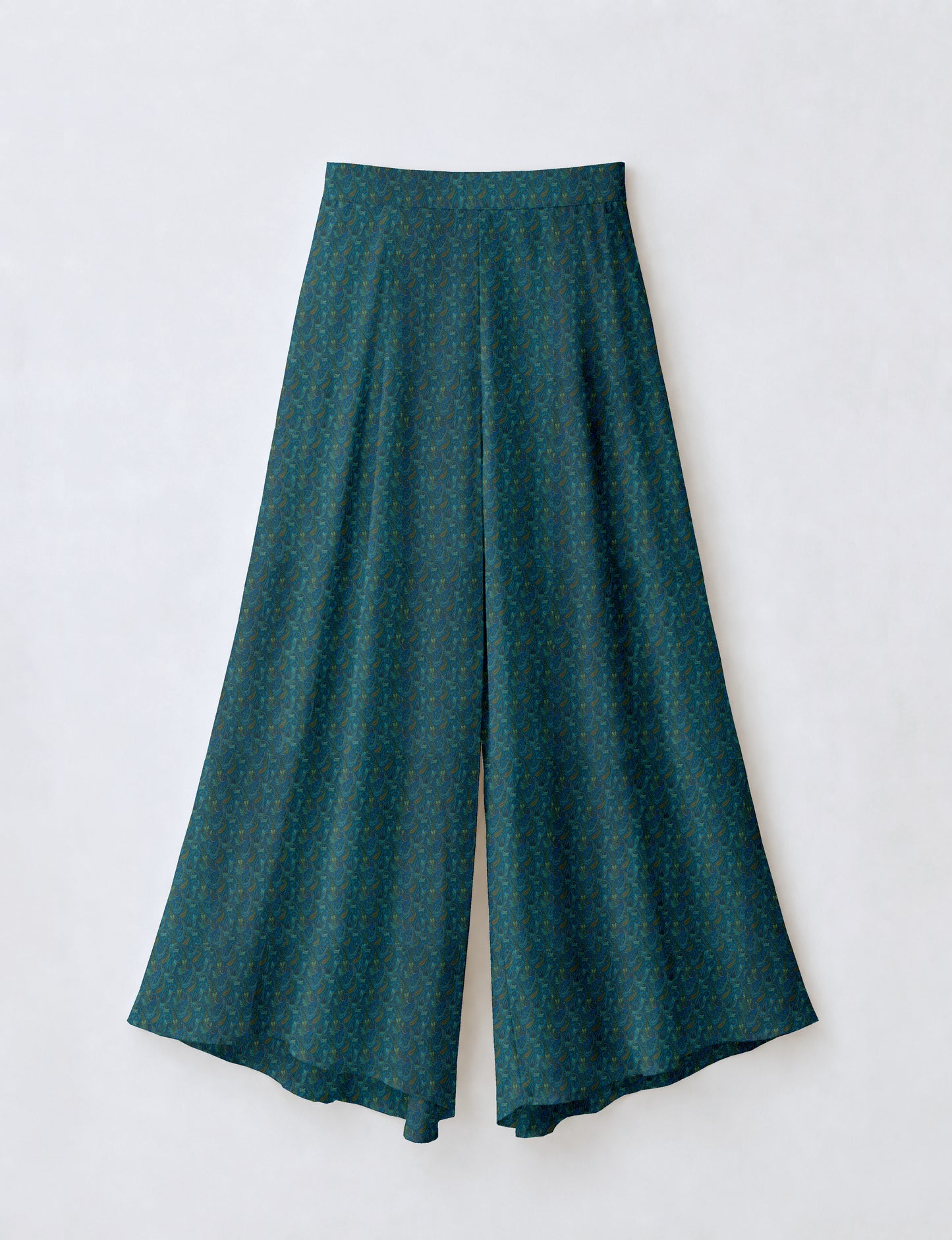 Woman wearing blue wide leg palazzo trousers with black and brown tropical floral print, side pockets, shown from back angle