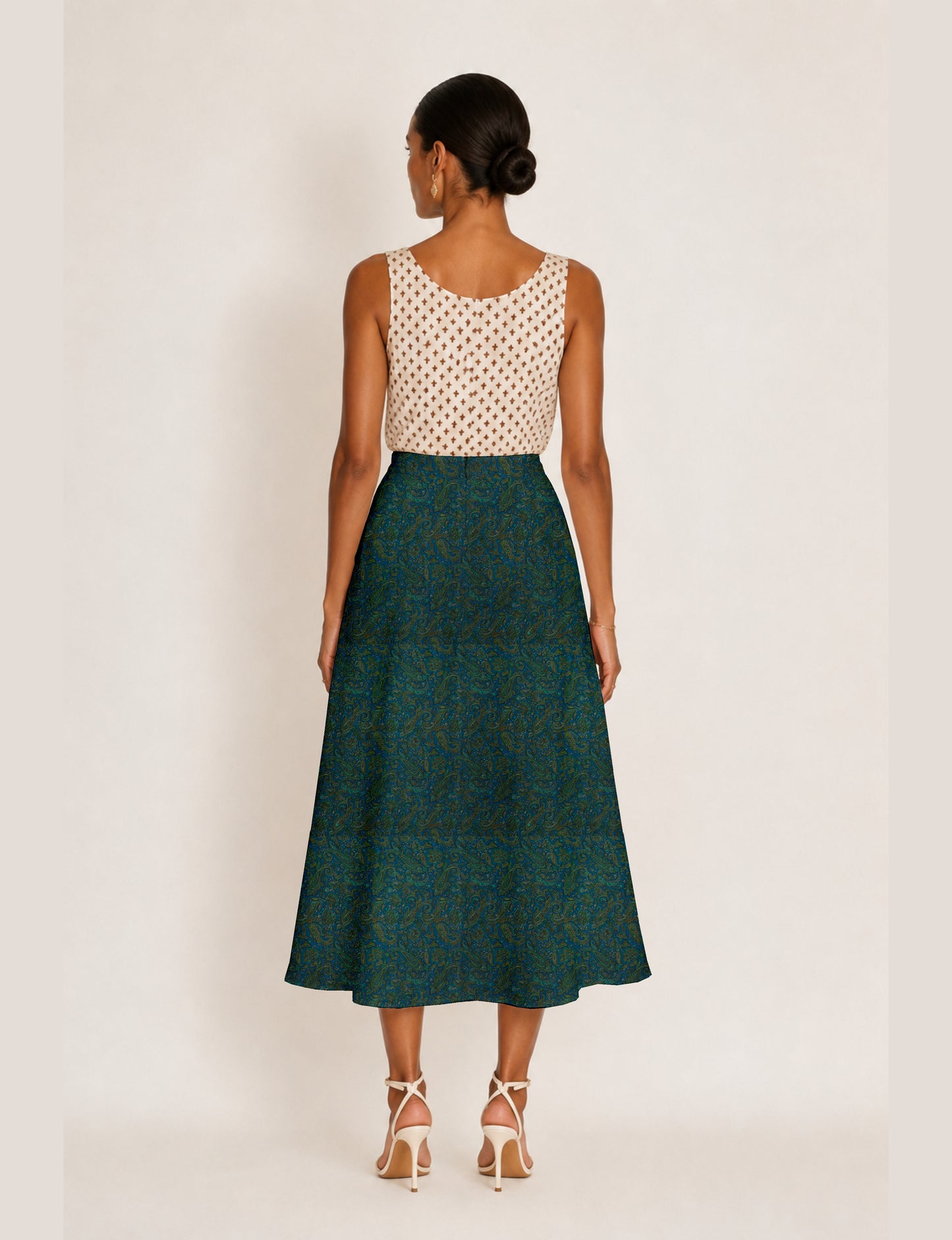 Woman wearing a yellow micro design A-line skirt with side slit, paired with a sleeveless beige top with small cross