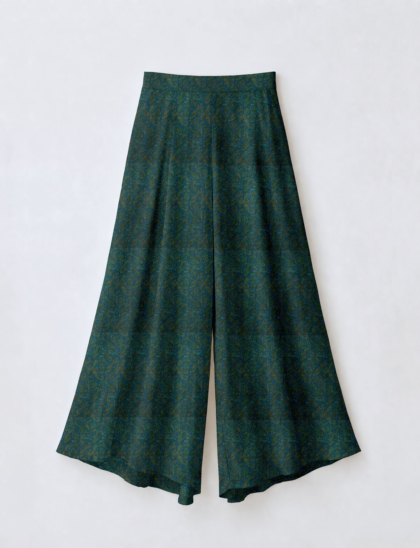 Woman wearing blue wide leg palazzo trousers with black and brown floral print, paired with brown sleeveless top and white