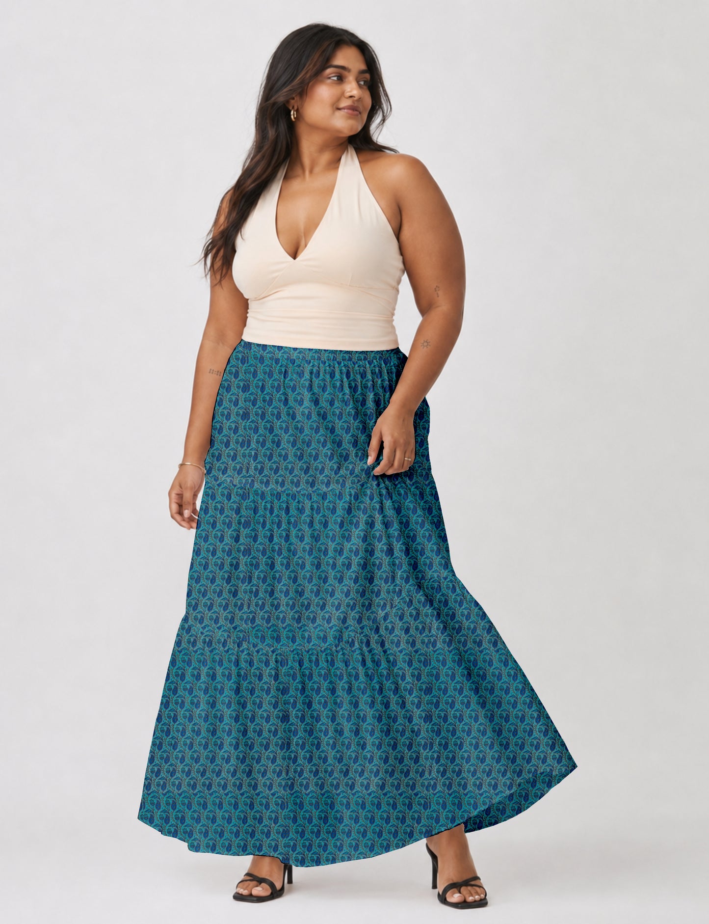Woman wearing a yellow midi tiered skirt with a small geometric pattern, paired with a beige strapless top and white heels