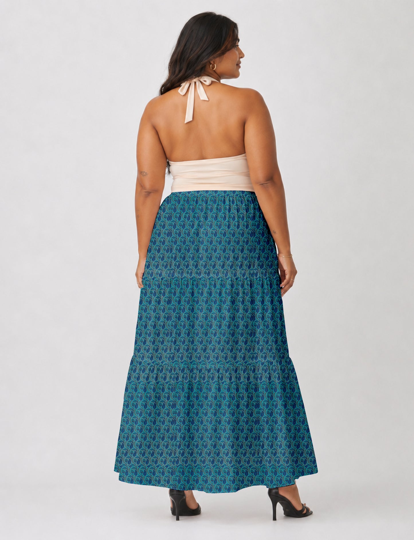 Woman wearing a yellow midi tiered skirt with a small geometric pattern, shown from the back, paired with beige top and