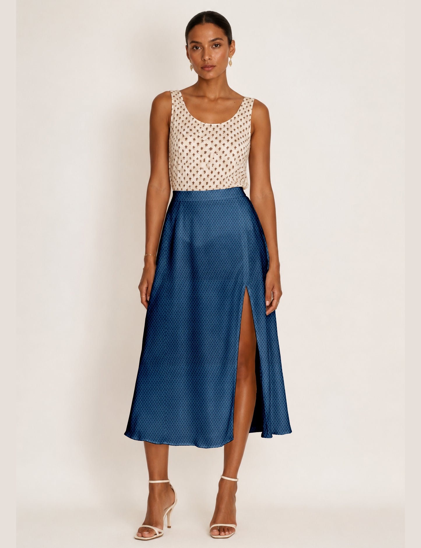 Woman wearing a yellow and black micro patterned A-line skirt with front slit, paired with beige sleeveless top and black