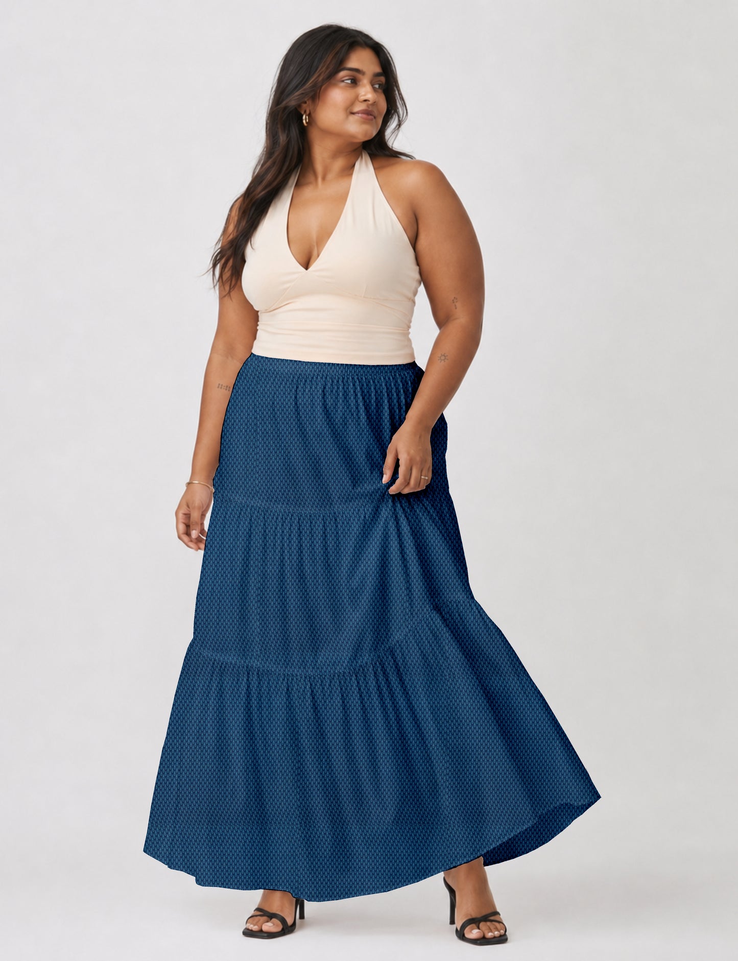 Woman wearing a yellow midi tiered skirt with a small geometric pattern, paired with a beige strapless top and white heels