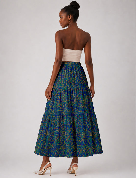 Woman wearing a yellow midi tiered skirt with a small geometric pattern, paired with a beige strapless top and white heels