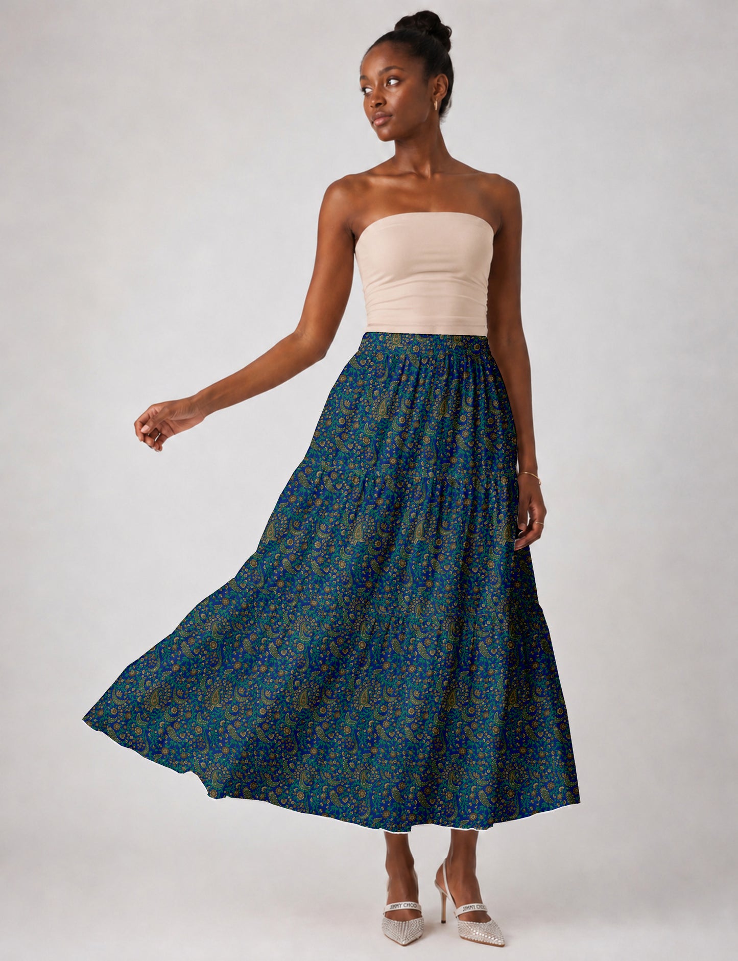 Woman wearing a yellow midi tiered skirt with a small geometric pattern, shown from the back, paired with beige top and