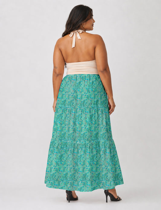Woman wearing a yellow midi tiered skirt with a small geometric pattern, paired with a beige strapless top and white heels