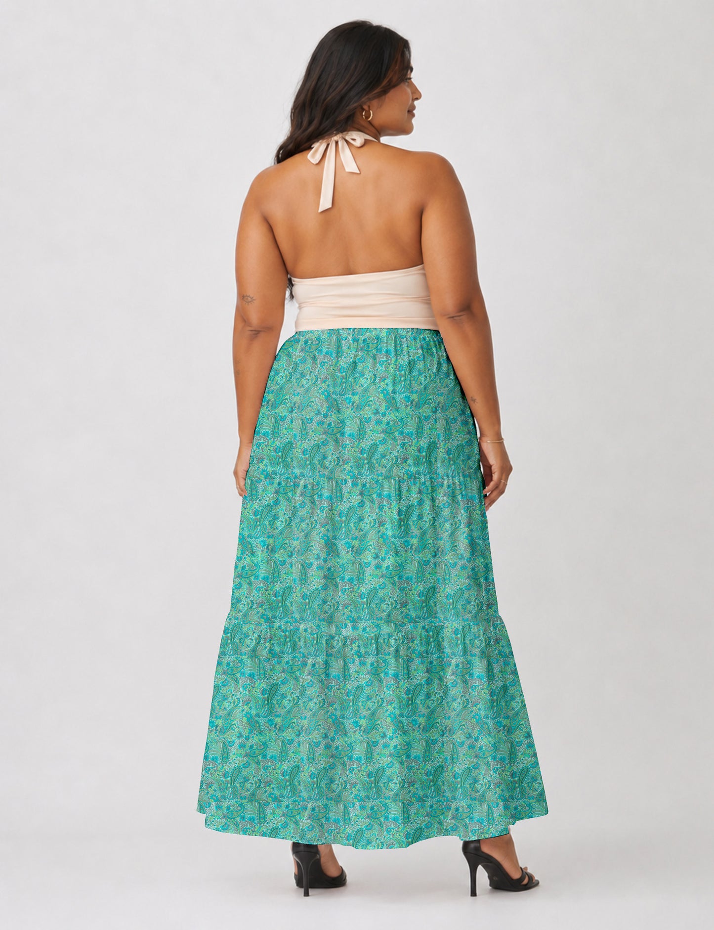 Woman wearing a yellow midi tiered skirt with a small geometric pattern, shown from the back, paired with beige top and