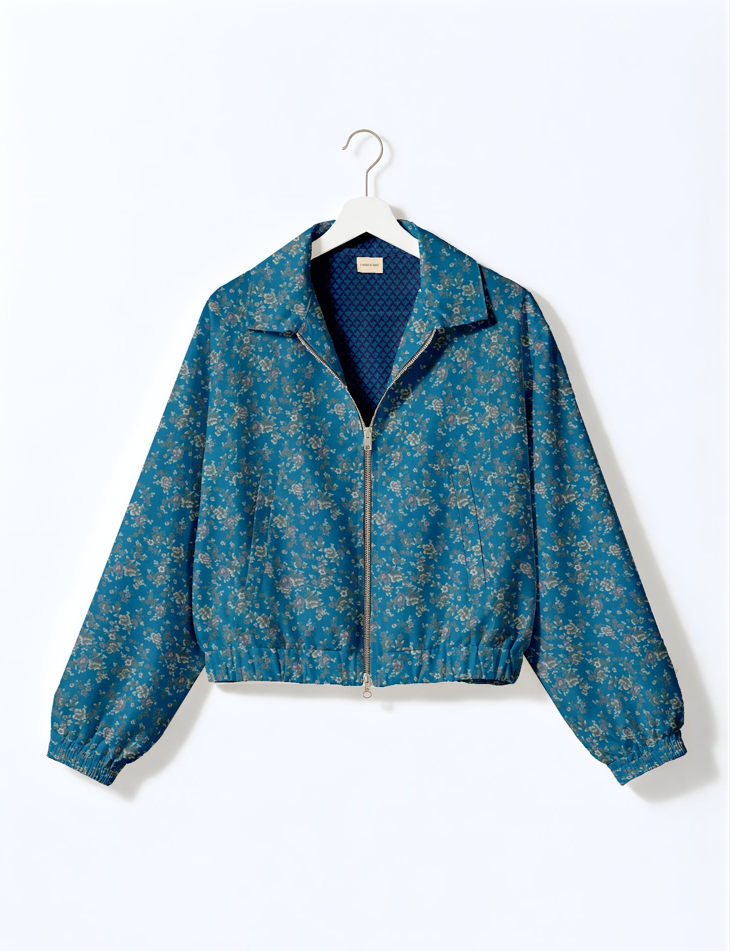 Women's cropped bomber jacket with twin metallic front zippers, welt pockets, elasticated hem and cuffs, and contrast sari print lining.