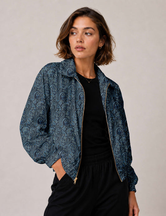 Woman wearing a yellow floral bomber jacket with front zipper, elastic cuffs, and side pockets, shown from front view