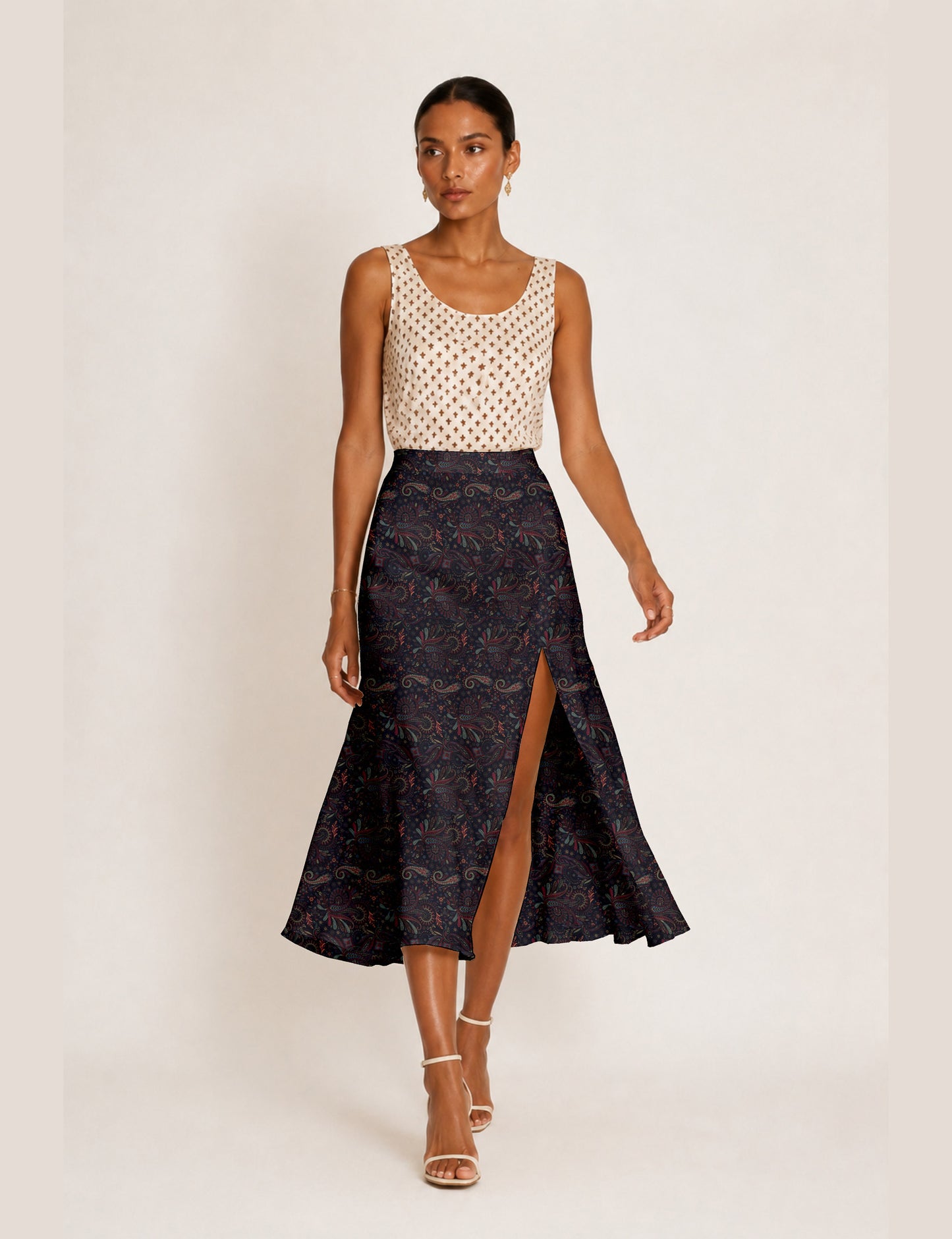 Woman wearing a yellow and black micro patterned A-line skirt with front slit, paired with beige sleeveless top and black