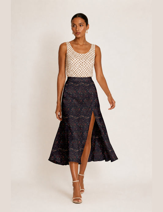 Woman wearing a yellow and black micro patterned A-line skirt with front slit, paired with beige sleeveless top and black