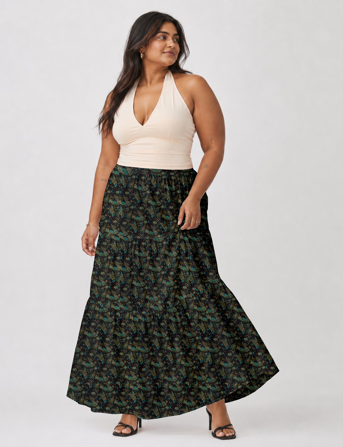 Woman wearing a yellow midi tiered skirt with a small geometric pattern, paired with a beige strapless top and white heels