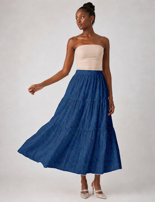 Woman wearing a yellow midi tiered skirt with a small geometric pattern, paired with a beige strapless top and white heels