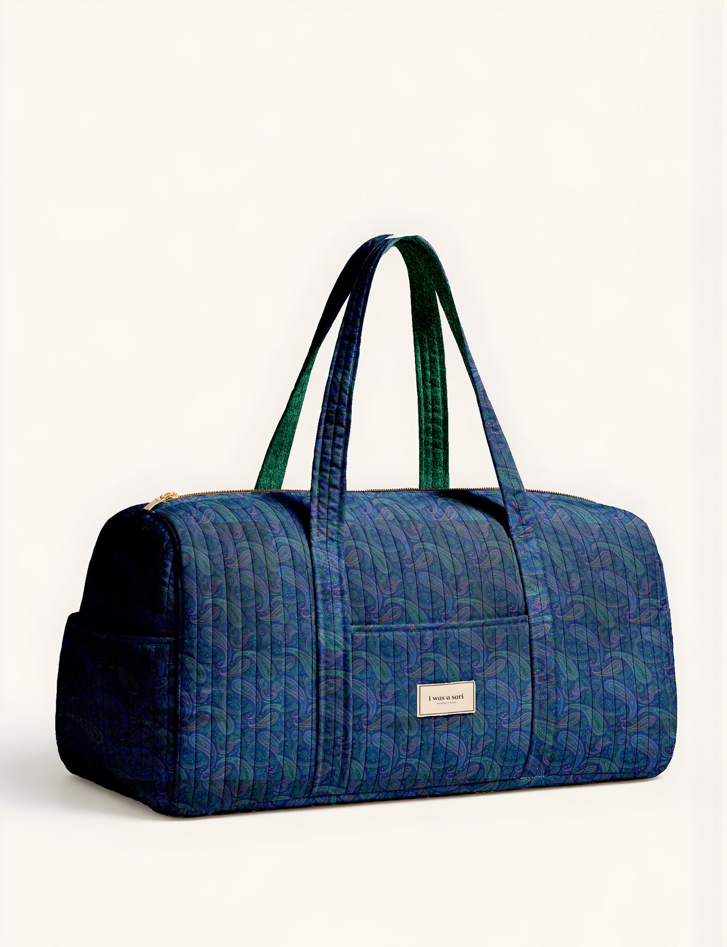 Quilted brown paisley barrel bag with double handles, front pocket, and gold zipper, shown in side angle view