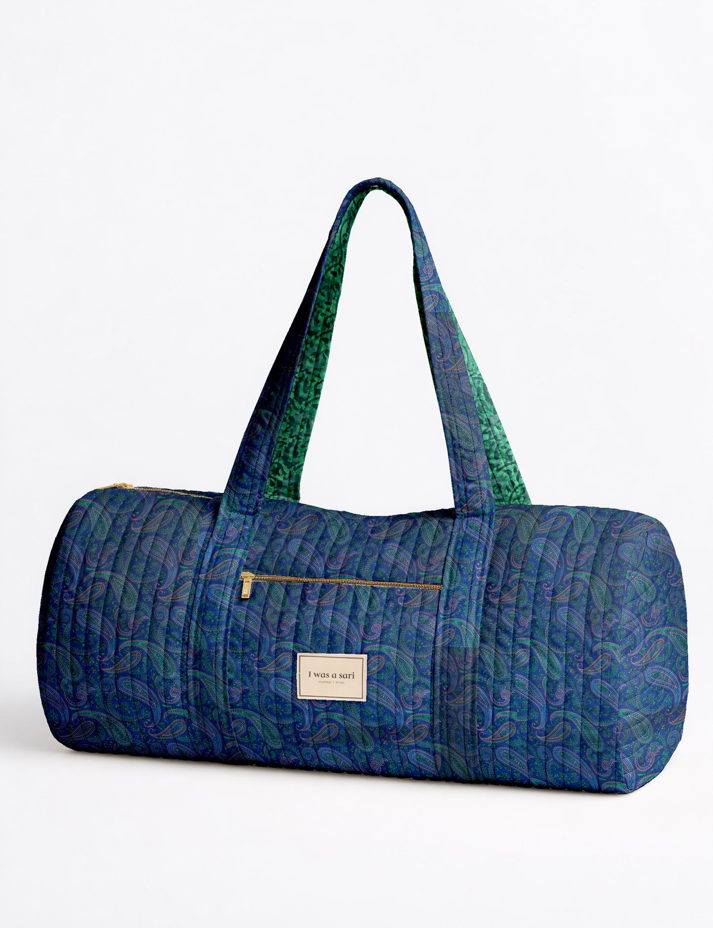 Brown paisley quilted bowling bag with front zipper pocket, held by person wearing white shirt and light blue jeans