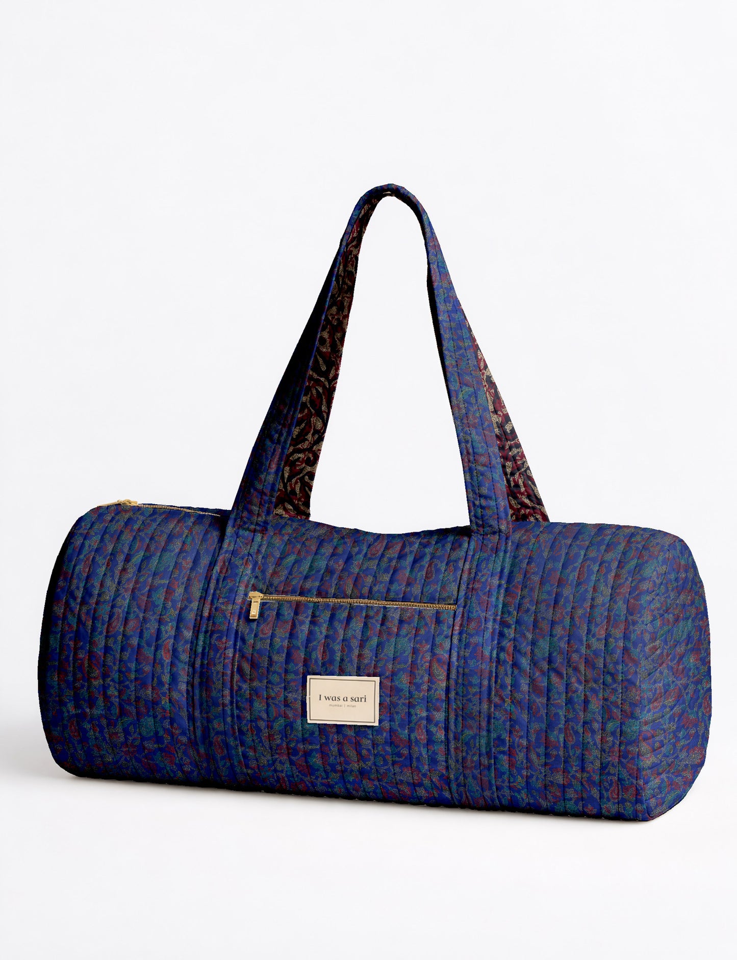 Brown paisley quilted bowling bag with dual handles, front zipper pocket, and "I was a sari" label on front side