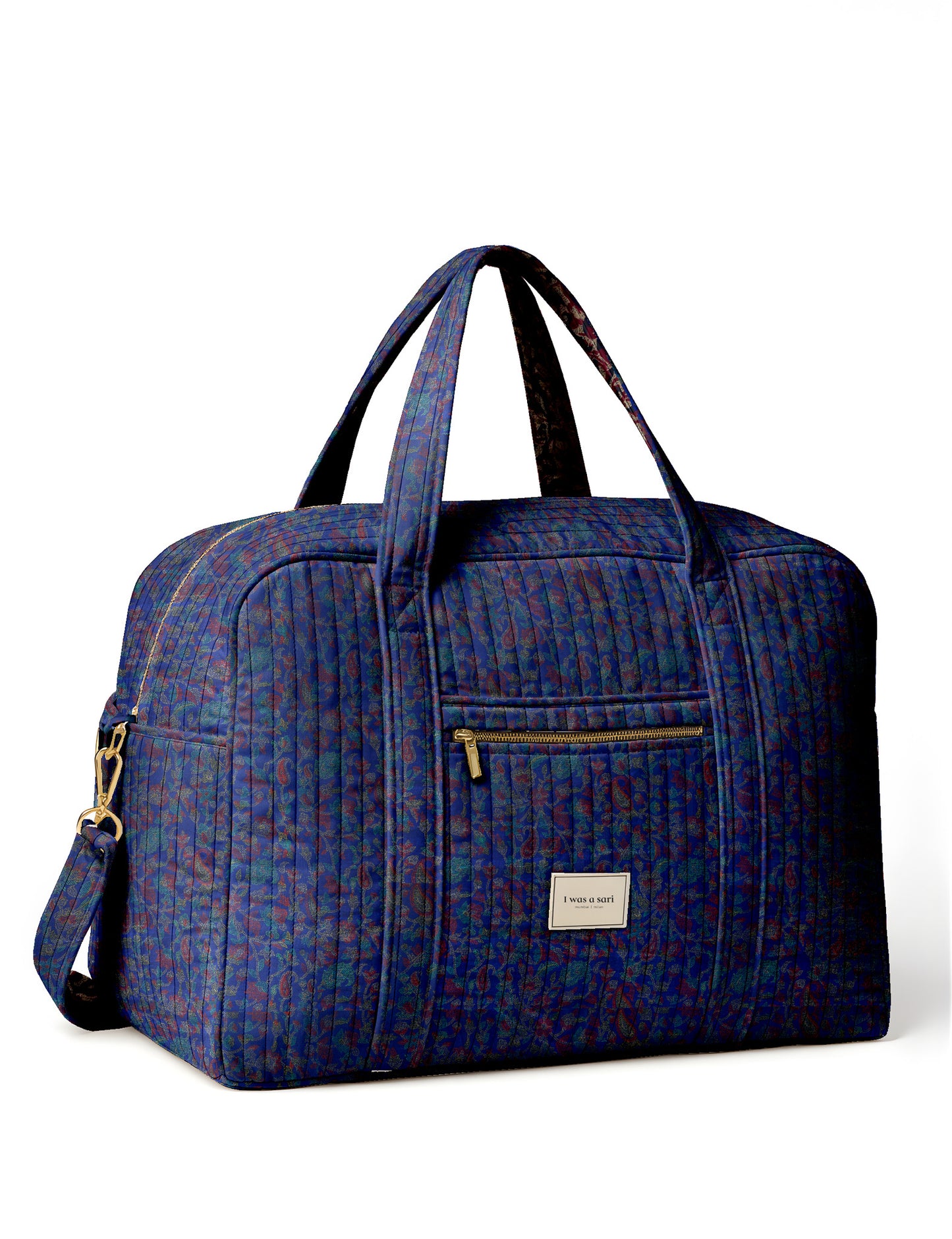 Brown quilted duffle bag with paisley pattern, front zip pocket, dual handles, and label reading "I was a sari"