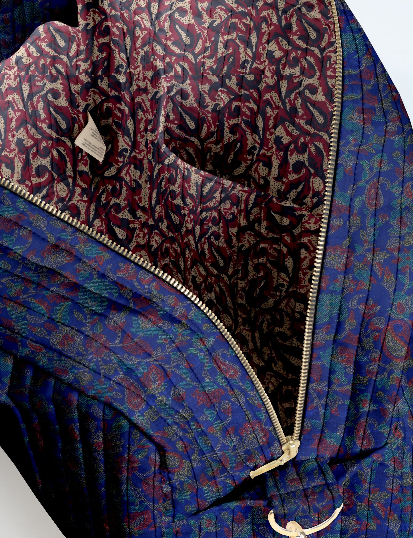 Brown quilted duffle bag with paisley pattern, front zip pocket, dual handles, and label reading "I was a sari"