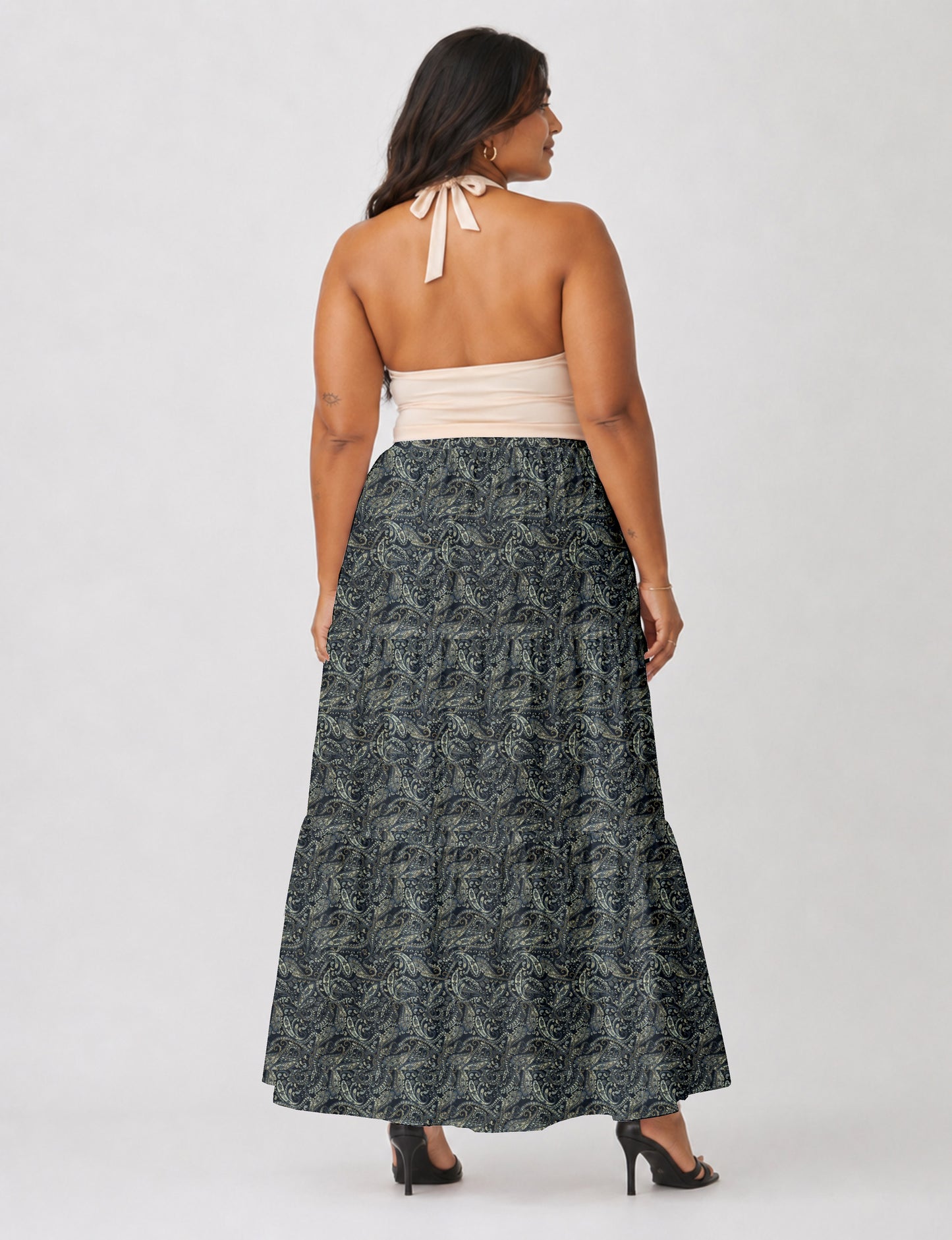 Woman wearing a yellow midi tiered skirt with a small geometric pattern, paired with a beige strapless top and white heels